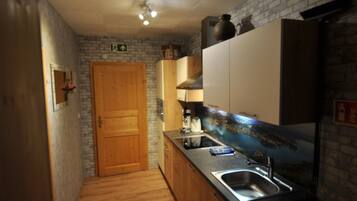 A narrow kitchen with wooden cabinets, a sink, and a stone wall.