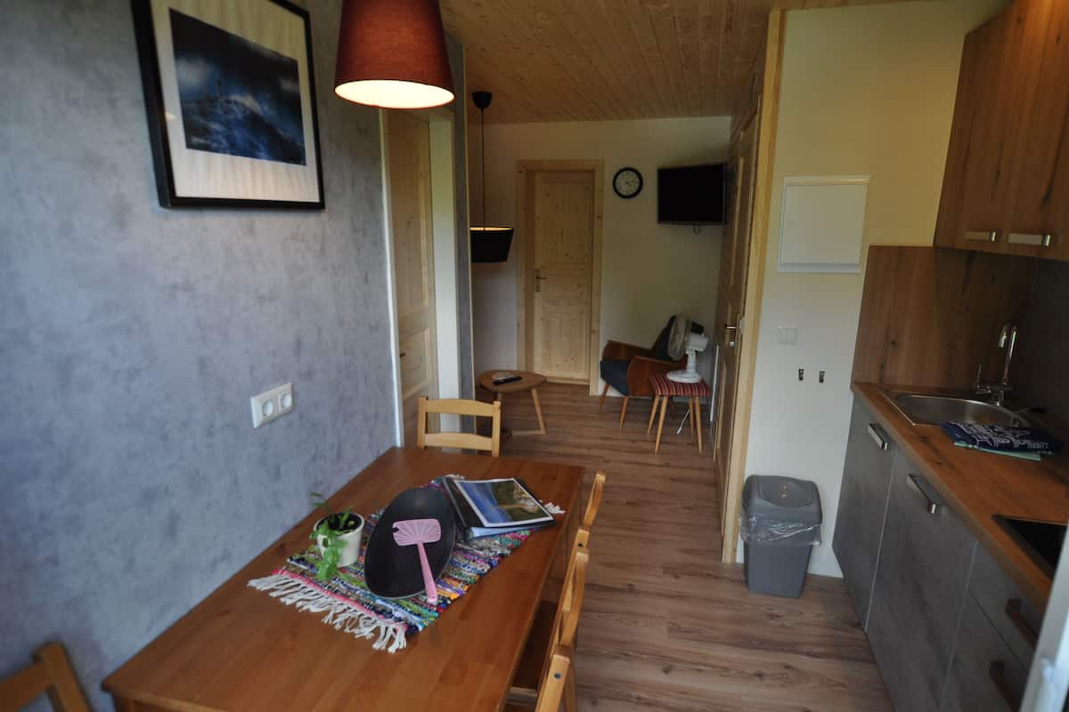 Eine kleine Küche mit Holzschränken, einem Spülbecken und einem Essbereich mit Tisch für zwei Personen.