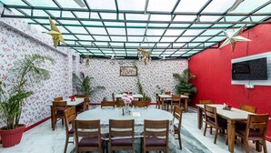 A dining area with a glass ceiling, floral wallpaper, and red walls. - Yorkshire inn (Abu Road)