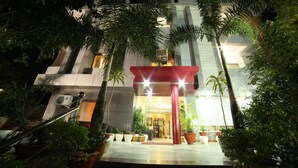 A modern hotel entrance with a red canopy, potted plants, and a well-lit facade. - Yorkshire inn (Abu Road)