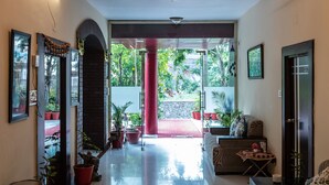 A spacious hallway with a ceiling fan, potted plants, and a view of the outdoors. - Yorkshire inn (Abu Road)