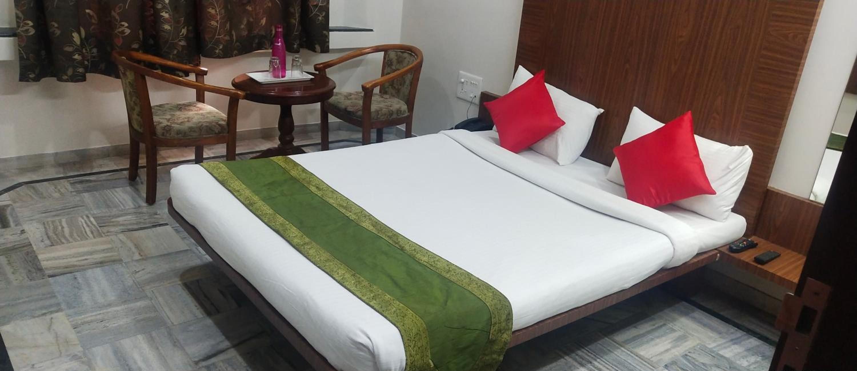 Une chambre d’hôtel avec un lit, deux chaises, une petite table et une table de chevet.