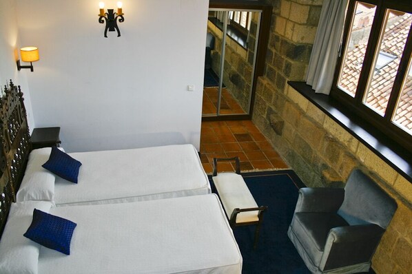 A hotel room with two beds, a chair, and a view of the outside through a window. - Saiaz Getaria Hotela (Getaria)