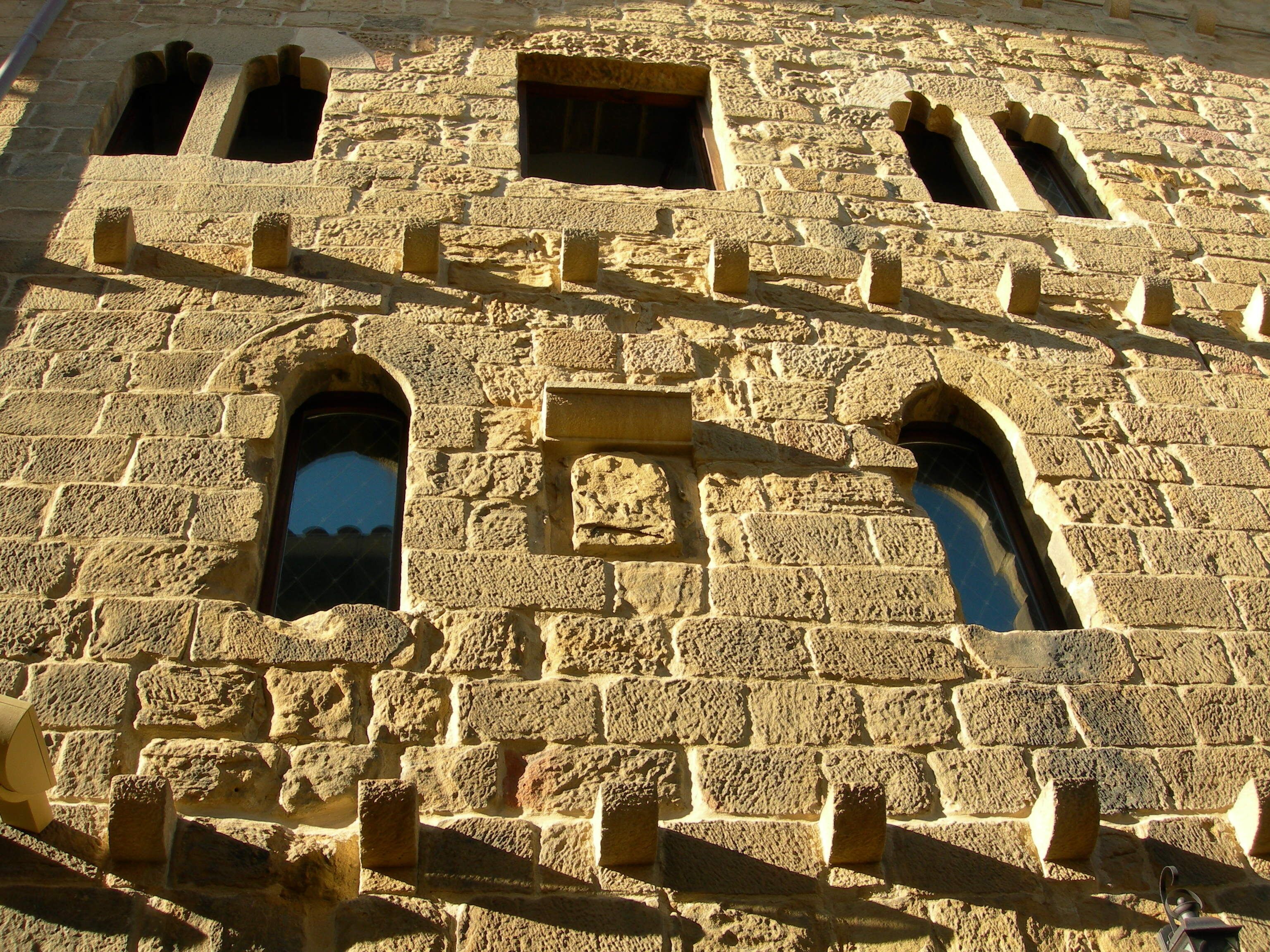 A stone building with multiple arched windows and a central square window.