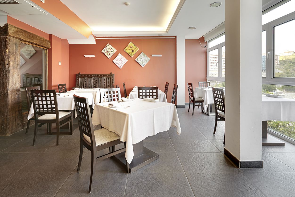 A dining area with tables set for four, wooden chairs, and a large window offering a view of the city.