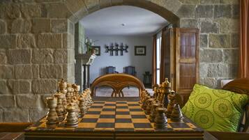 A chessboard set up on a table in a room with stone walls and a wooden door.