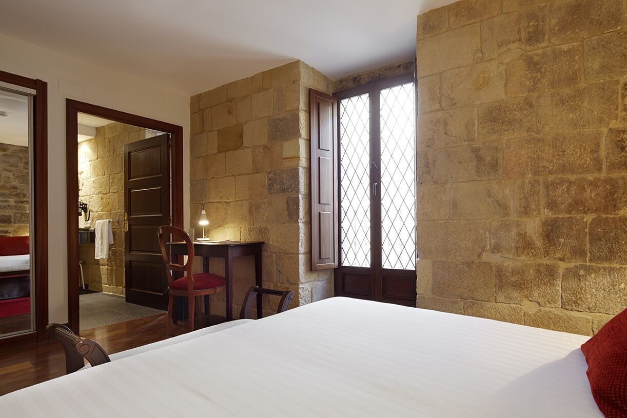 Un dormitorio con una cama grande, un escritorio con una silla y una ventana con vistas al exterior.