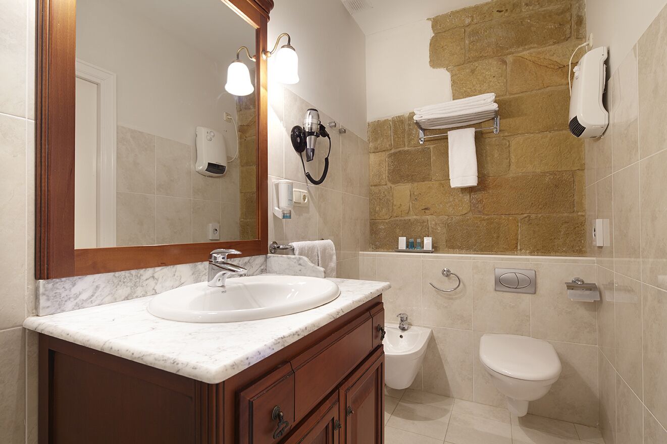 A bathroom with a marble sink, a bidet, a toilet, and a towel rack.