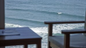 A view of the ocean from a window with a wooden table in the foreground. - Saiaz Getaria Hotela (Getaria)