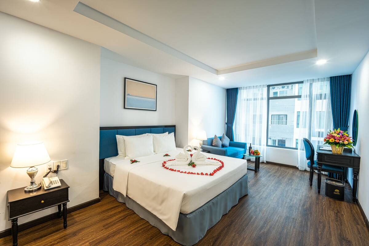 Een hotelkamer met een groot bed, een bureau, een stoel, een lamp en een telefoon op een nachtkastje.