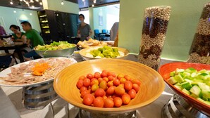 A buffet with various dishes including a large bowl of oranges, a bowl of green vegetables, and a plate of sliced cucumbers. - Paralia Hotel Nha Trang (Bac Nha Trang)