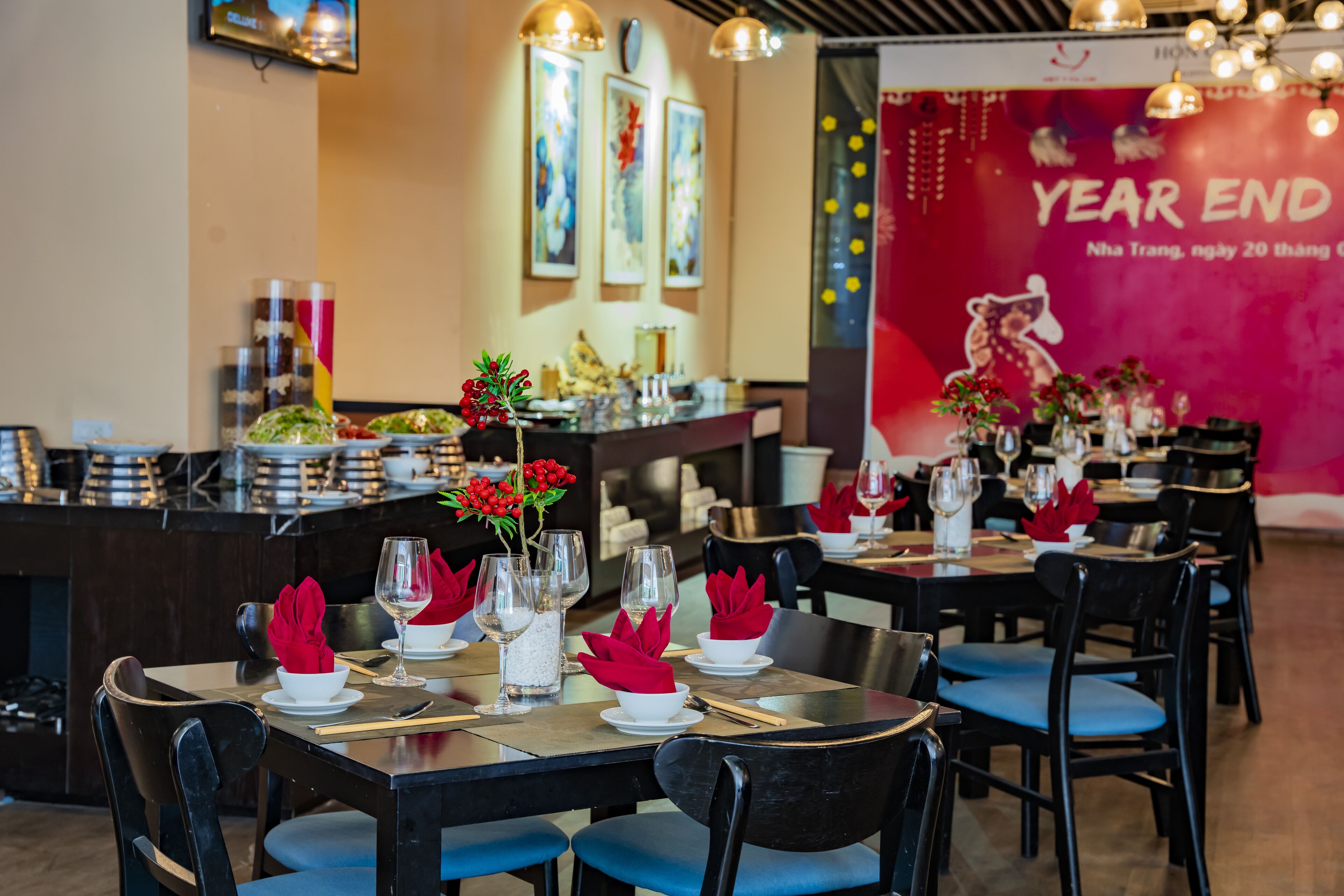 Un restaurante con mesas dispuestas para comer, con servilletas rojas y platos blancos.