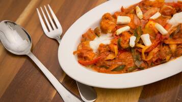A white plate of food with a fork and spoon on a wooden table.