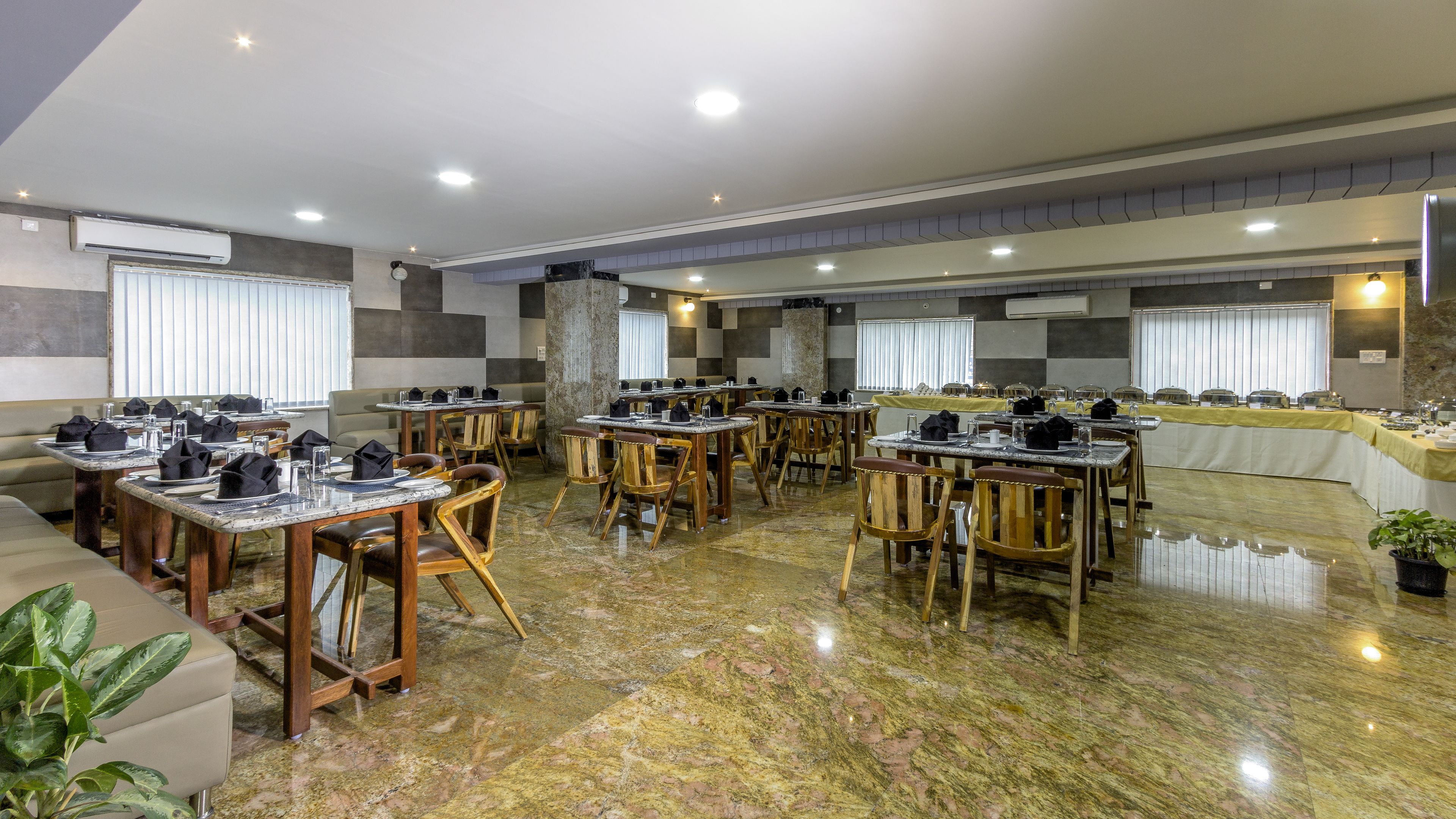 A spacious dining area with multiple tables and chairs, air conditioning units, and a polished marble floor.