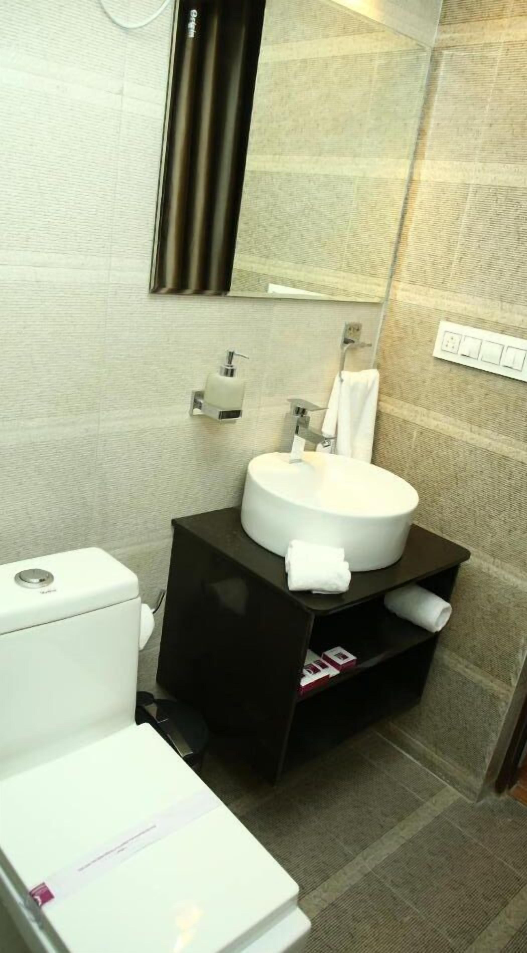 A modern bathroom with a white sink, dark vanity, and a mirror above the sink.