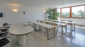 Una sala conferenze con un grande tavolo ovale, diverse sedie e un proiettore.