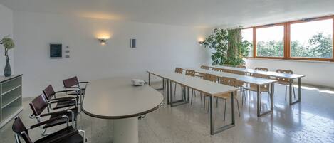 A conference room with a large oval table, multiple chairs, and a projector.