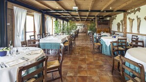 A restaurant with wooden beams, tiled floors, and tables set for dining. - Costa degli Ulivi (Fumane)