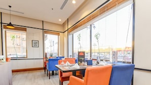 Ein Restaurantinnenraum mit Tischen, Stühlen, großen Fenstern und Blick auf die Straße.