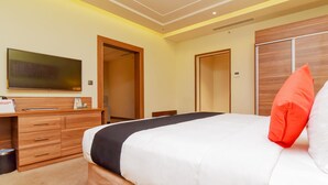 Ein Hotelzimmer mit Bett, Schreibtisch mit Schubladen, Fernseher und Kleiderschrank.