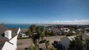 A coastal residential area with houses, a clear sky, and a view of the sea.