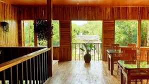 Ein Holzinnenraum mit Balkon, großen Fenstern und einem Essbereich mit Stühlen und Tisch.