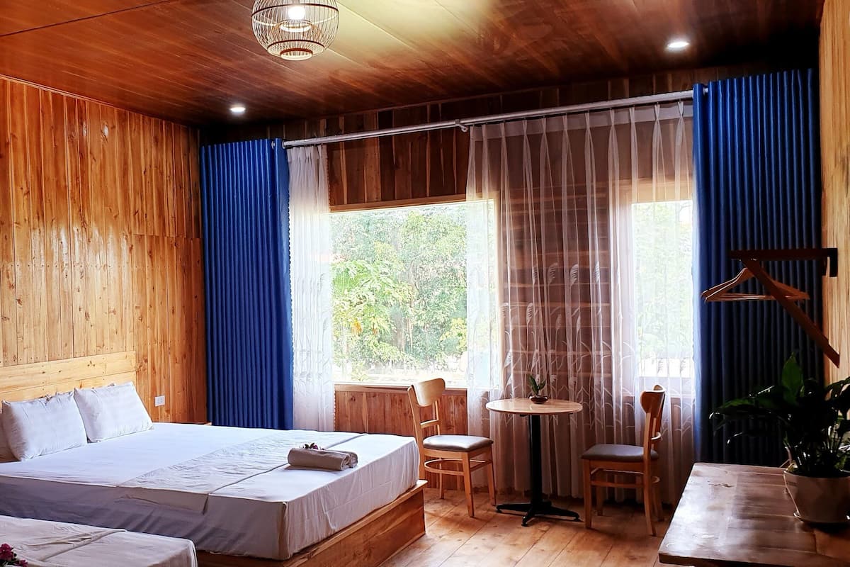 A wooden-paneled room with two beds, a small table, and a chair.
