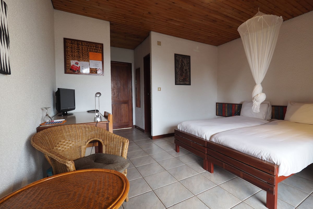 Une chambre d’hôtel équipée d’un lit, d’une chaise, d’un bureau avec un ordinateur et d’un téléviseur fixé au mur.