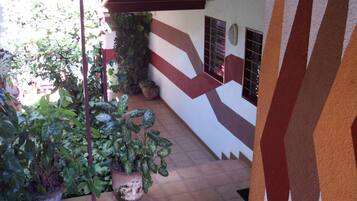 A covered outdoor area with potted plants and a tiled floor.