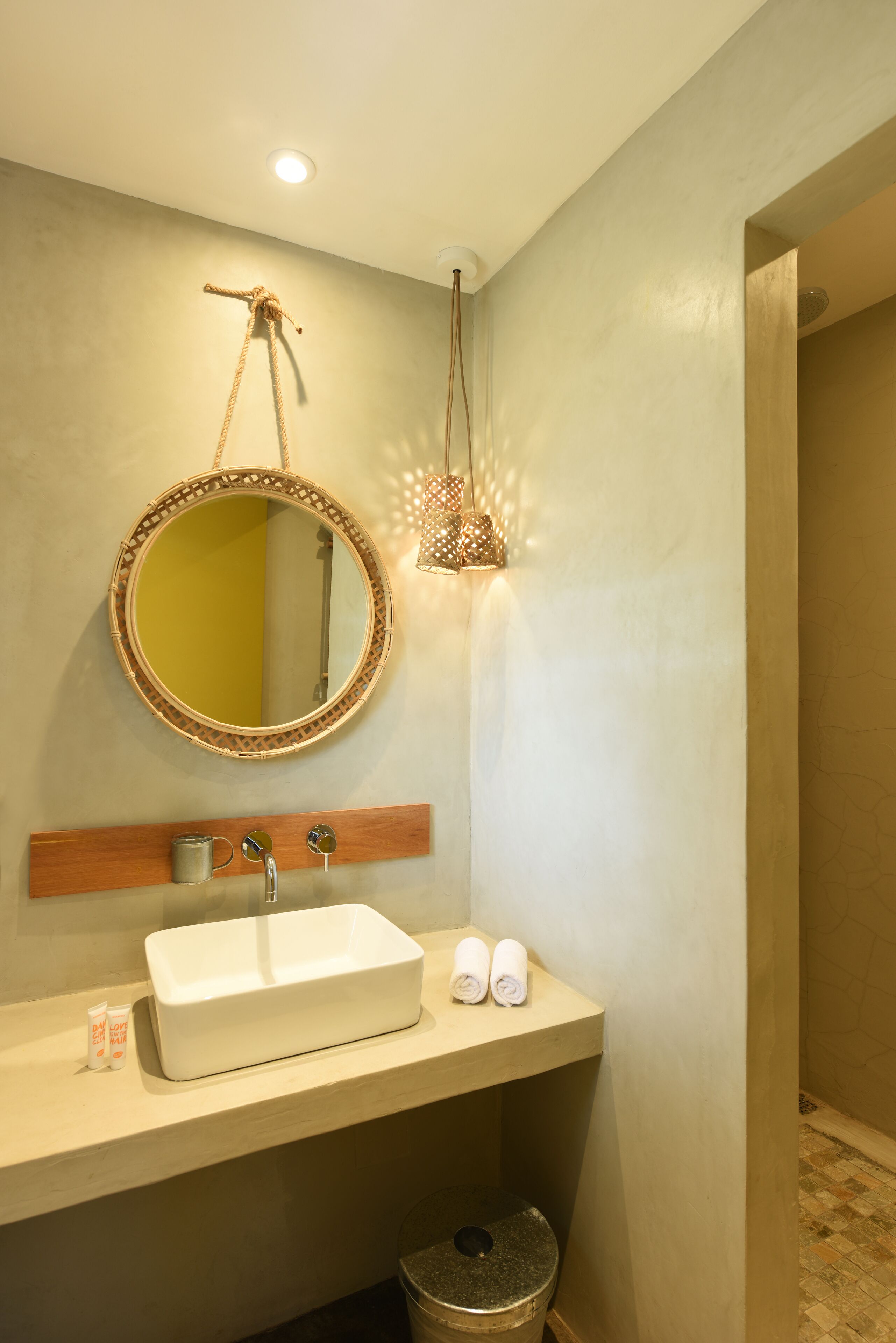 A bathroom with a white sink, a round mirror with a decorative frame, and a hanging light fixture.