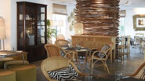 Een eetgedeelte met rieten meubels, een houten kast en een hanglamp.