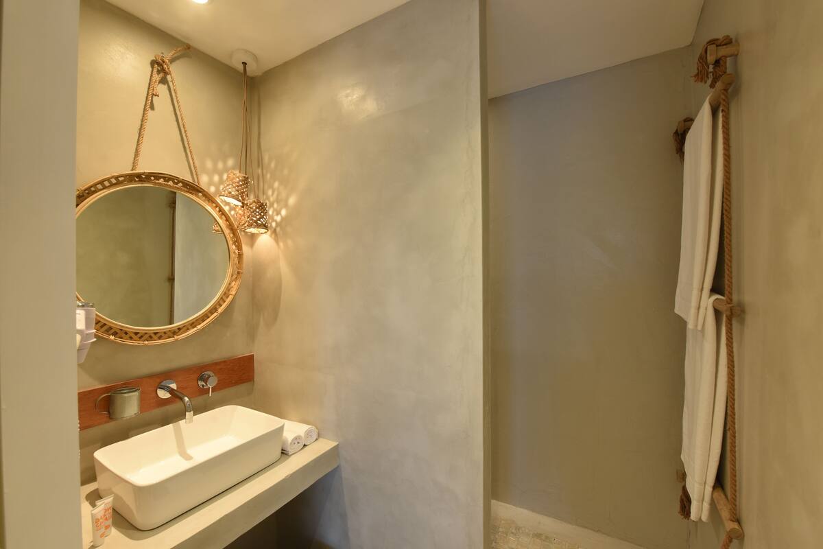 A bathroom with a white sink, a round mirror with a wooden frame, a towel rack, and a shower curtain.