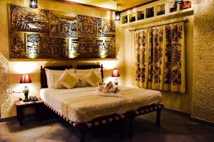 Quarto tradicional com cama, arte decorativa na parede e cortina estampada.