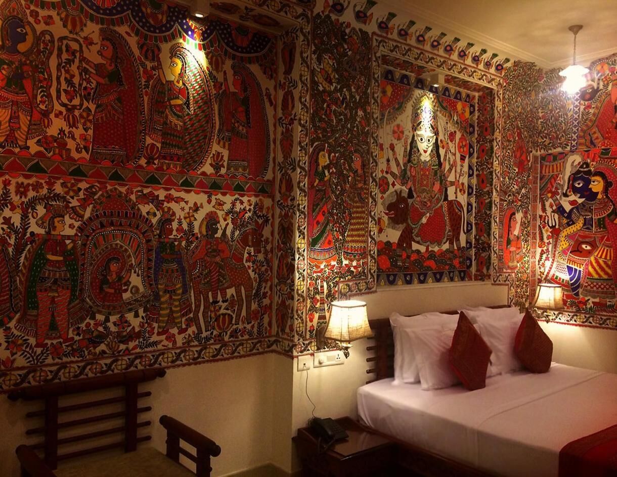 Une chambre avec un lit, une table de chevet et une tapisserie murale.