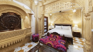 Una habitación ricamente decorada con una cama grande, intrincados relieves en las paredes y un suelo con diseños.