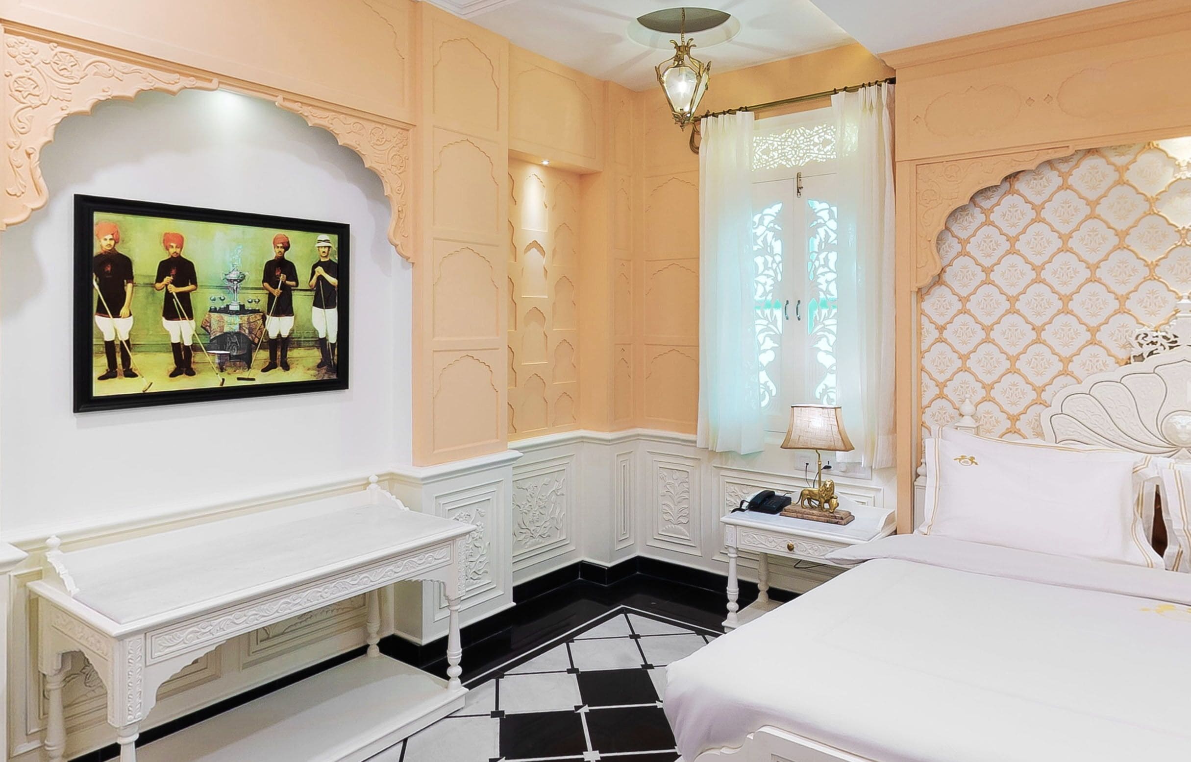 A hotel room with a bed, a nightstand, a bench, and a wall-mounted television.