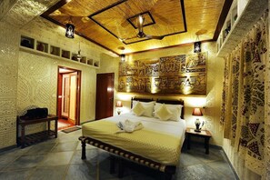 Una habitación con una cama grande, techo de madera y decoraciones murales detalladas.