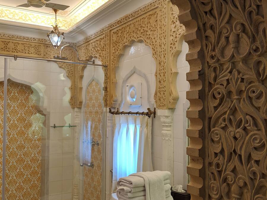 Een badkamer met decoratieve wanddecoraties, een douche met glazen deuren en een toilet met een handdoekhouder.