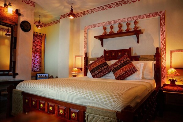 Una habitación tradicional con una cama grande, cabecera de madera, almohadones estampados y adornos en la pared.