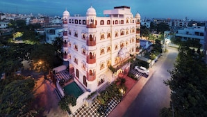 Un edificio de varios pisos con un patio central, rodeado de árboles y una piscina.