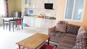 A compact living space with a dining area, kitchenette, and a sofa set. - Shine Nepal Homestay (Kathmandu)