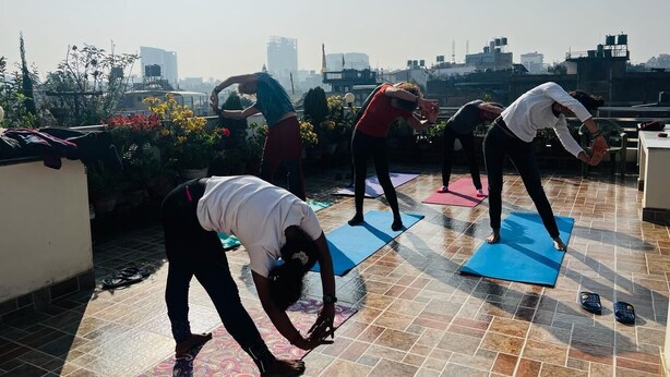 A rooftop yoga class with participants on mats, surrounded by potted plants and a cityscape view. - Shine Nepal Homestay (Kathmandu)