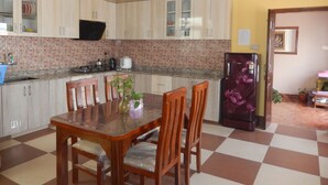 A kitchen with a dining table and chairs, a refrigerator, and cabinets. - Shine Nepal Homestay (Kathmandu)