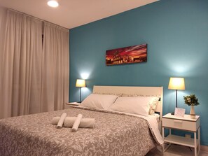 A hotel room with a bed, two bedside tables with lamps, a painting of a cityscape, and a window with curtains. - amoRaRoma (Rome)