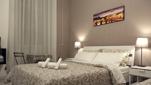 Quarto bem arrumado com uma cama grande, duas mesas de cabeceira com abajures, uma cadeira e um quadro na parede.