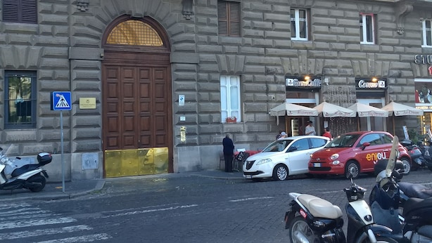 Um edifício histórico com uma grande porta de madeira, um café e um restaurante.