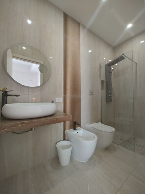 A modern bathroom with a large mirror, a sink, a bidet, a toilet, and a glass-enclosed shower. - Villa Felice (Porto Cesareo)