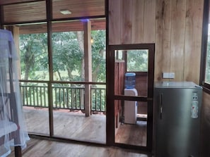 A wooden-framed room with a sliding glass door leading to an outdoor balcony. - Green herbal Ayurvedic Eco-Lodge (Unawatuna)