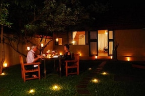 An outdoor dining area with a table and chairs, surrounded by a garden with small lights. - Green herbal Ayurvedic Eco-Lodge (Unawatuna)