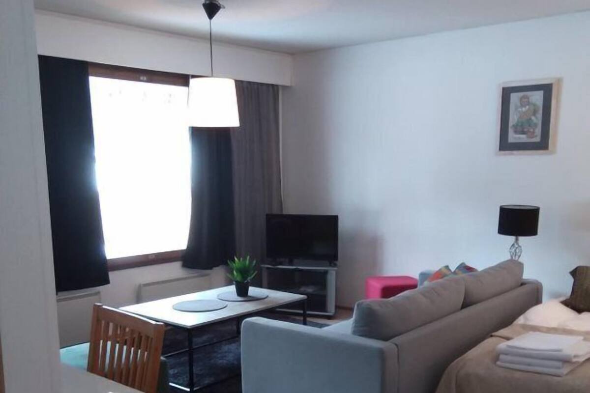 A compact living space with a dining area, a sofa, a TV, and a lamp.